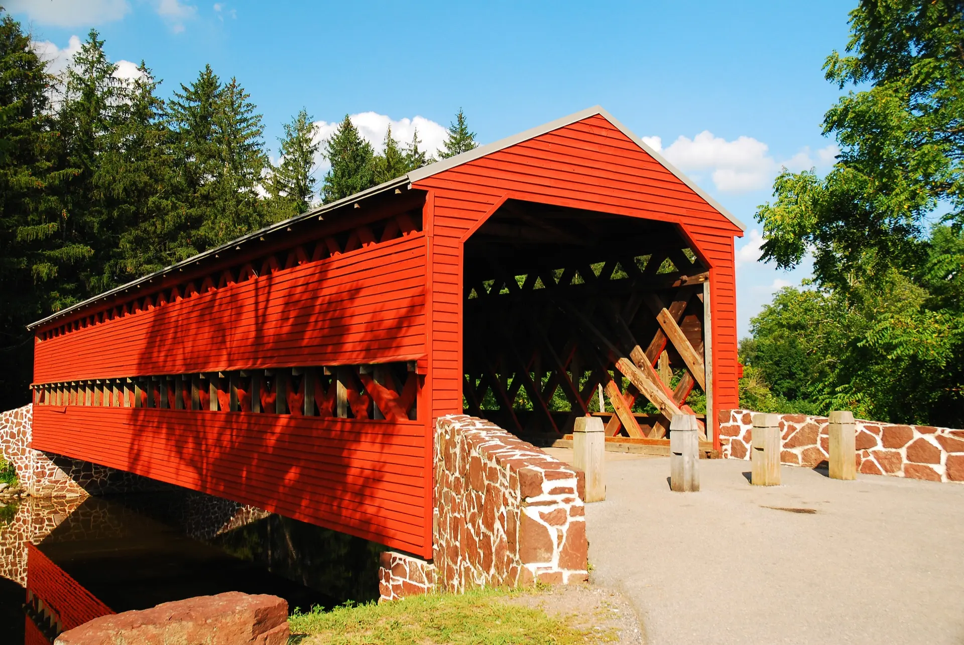 Eine rote überdachte Brücke zwischen Bäumen im Frühling